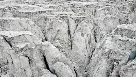 Aerial-flyover-over-the-Moiry-glacier-near-Grimentz-in-Valais,-Switzerland-with-a-pan-down-view-straight-into-an-ice-crevasse