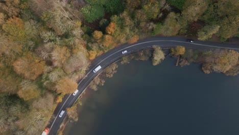 Statischer-Blick-Nach-Unten-Drohnenaufnahme-Einer-Farbenfrohen-Sonnigen-Herbstbaumszene-Mit-Vorbeifahrenden-Autos-Neben-Dem-Lake-Windermere-Ambleside-Cumbria