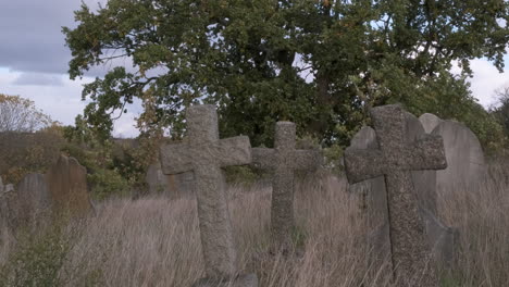 Three-Crucifix-Cross-Shaped-Headstones-in-Overgrown-Abandoned-Cemetery
