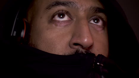 Close-Up-Shot-Of-Bangladeshi-Gamer-Wearing-Headset-And-Hoodie-Zipped-Up-To-Mouth,-Looking-With-Eyes