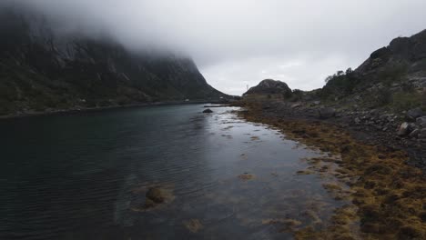 Am-Ufer-Entlangfliegen-Nah-Ans-Wasser-Schauend,-Links-Sind-Die-Berge-In-Nebel-Gehüllt