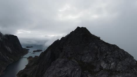 Flying-along-a-mountain-ridge-in-Norway,-on-the-right-no-view-through-fog-and-on-the-left-the-view-of-the-ocean-in-the-background,-in-slowmotion