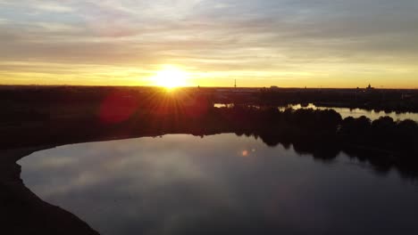 Bright-sunshine-during-golden-sunset-over-lake-landscape-of-Belgium,-aerial-view