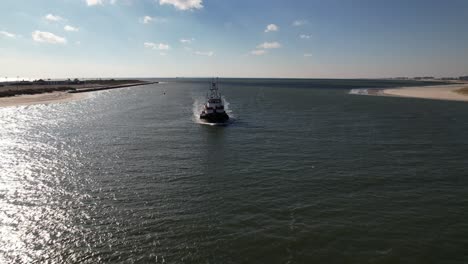 An-aerial-view-of-a-tugboat-on-a-sunny-day-in-the-East-Rockaway-Inlet-in-Queens,-NY