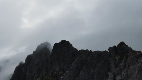 Flying-along-a-mountain-ridge-in-Norway,-on-the-right-no-view-through-fog-and-on-the-left-the-view-of-the-ocean-in-the-background,-at-the-end-flying-into-the-fog,-in-slowmotion
