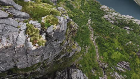 Cliffdiving-in-Norway-overlooking-the-coast,-the-ocean-and-a-bridge-starting-at-the-peak-of-a-mountain