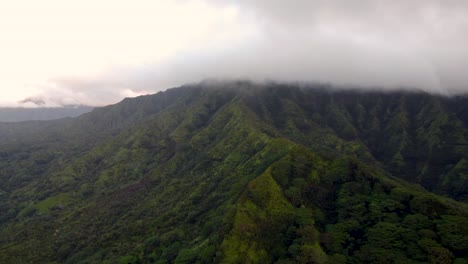 Cinematic-flyover-at-beautiful-sunrise-on-Kauai-Hawaii-island-revealing-green-mountains-under-tropical-rain-clouds