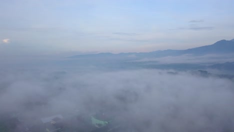 Aerial-flyover-rural-landscape-with-sea-of-fog-in-Indonesia-after-sunset