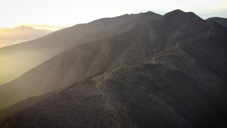 Umlaufende-Drohnenaufnahme-Von-Wanderern-Auf-Einem-Hügel-Bei-Sonnenaufgang-In-Den-Nebligen-Bergen-Von-Lima,-Peru