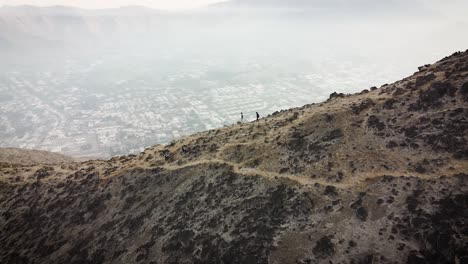 Kreisende-Drohnenaufnahme-Von-Wanderern,-Die-Einen-Kamm-In-Den-Bergen-Der-Stadt-Lima,-Peru,-Hinuntergehen