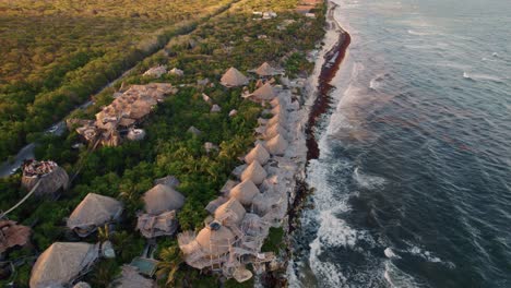 Kreisen-Um-Den-Panoramablick-Auf-Das-Resort-Azulik-In-Tulum-Mexiko-Im-Magischen-Goldenen-Licht-Des-Sonnenuntergangs-Mit-Wellen,-Die-Von-Der-Karibischen-Küste-Hereinbrechen