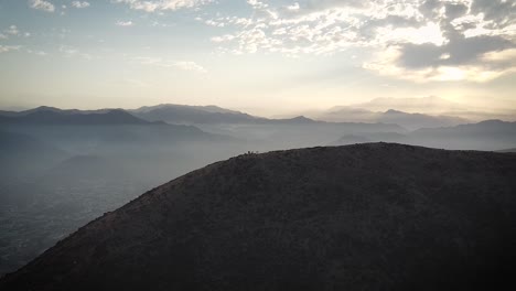 Landschaftsdrohnenaufnahme-Von-Wanderern-Auf-Einem-Hügel-Bei-Sonnenaufgang-In-Den-Nebligen-Bergen-Von-Lima,-Peru