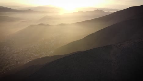 Drone-shot-of-light-beams-in-the-misty-hills-of-Lima-Peru-during-sunrise