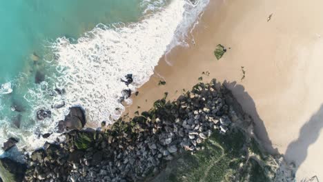Aerial-view-of-the-ruins-of-an-old-lighthouse-by-the-sea-and-the-beach-on-a-sunny-day