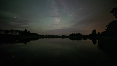 Night-starry-cloudy-sky-above-reflective-lake-water,-fusion-timelapse