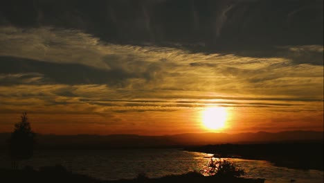 Sonnenuntergang-Orange-Licht-Schwarz-Berg--Und-Wasserlandschaft