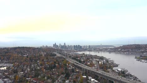 Wide-aerial-view-of-Seattle's-traffic-flowing-underneath-with-Lake-Union-and-the-Space-Needle-on-the-horizon