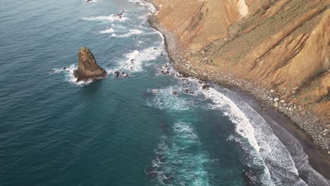 Aerial-view-of-a-black-sand-beach-with-ocean-waves-breaking-on-the-shore