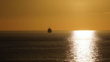 Hinter-Sauberem-Land-Bewegt-Sich-Ein-Boot-Während-Des-Majestätischen-Sonnenuntergangs-über-Den-Ozean
