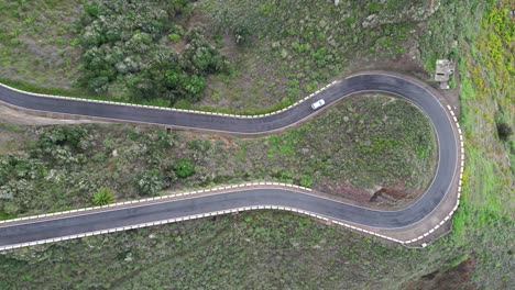 Aerial-view-of-a-car-driving-on-a-curvy-mountain-road