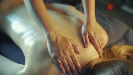 The-masseur-massages-the-girl's-back-with-massage-oil-from-bottom-to-top