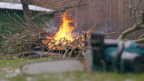 Brennender-Haufen-Hochgeschobener-Äste---Grünabfallbeseitigung-Bei-Frühjahrsarbeiten