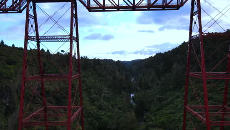 Lowering-drone-shot-of-red-railway-bridge-over-george-with-trees-and-river