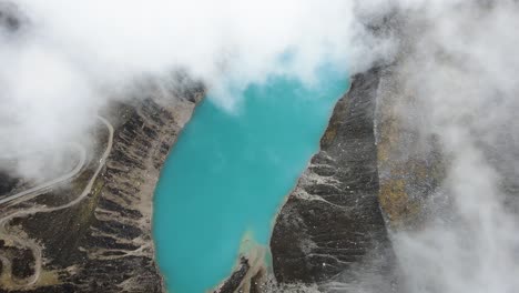 Drone-shot-of-a-blue-lake-from-above-the-clouds-in-the-highlands-of-Huaraz-Peru