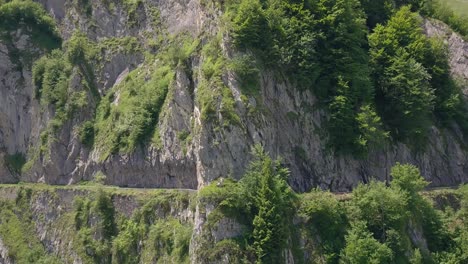 Die-Drohnenansicht-Schwenkt-Um-Einen-Epischen-Felstunnel-Herum,-Während-Vier-Radfahrer-Auf-Einer-Radtour-Den-Pass-Warfen-Und-Auf-Der-Anderen-Seite-In-Den-Bergen-Der-Französischen-Pyrenäen-Abfahren