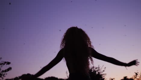 A-Female-Silhouette-Gracefully-Dancing-Under-The-Purple-Sky-During-Sunset-With-Bats-Flying---Close-up-Shot