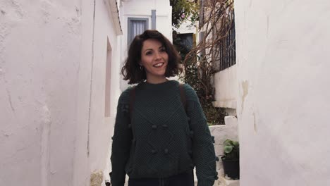 Slow-motion,-young-woman-walks-down-narrow-alley-smiling,-in-Anafiotika,-Athens,-Greece,-gimbal-medium-shot
