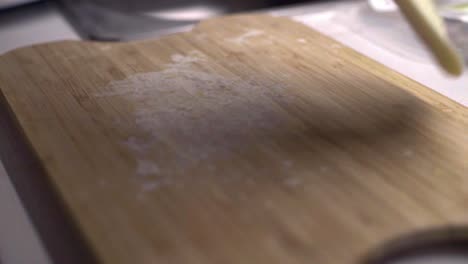 Caucasian-hands-pick-up-flat-raw-thin-dough,-slide-and-flip-over-on-wood-board
