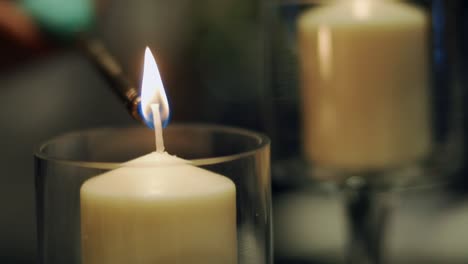 White-candles-inside-a-glass-candle-holder-being-lit