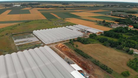 Rows-of-white-greenhouses-nestled-between-fertile-farmland,-Osijek-Baranja-County,-Croatia,-aerial