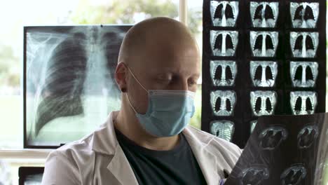 Radiologist-doctor-with-face-mask-examining-an-Xray-film,-profile-view