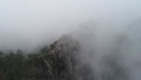 Aerial-pan-of-mountain-peak-in-Mexico-being-engulfed-by-grey-dark-rain-clouds