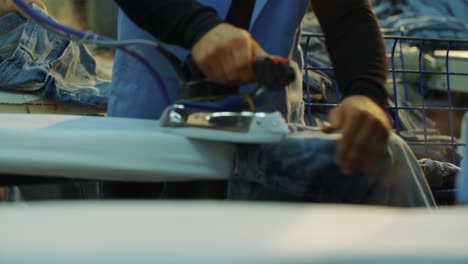 En-La-Fábrica-De-Producción-De-Jeans,-Los-Trabajadores-Planchan-Los-Jeans