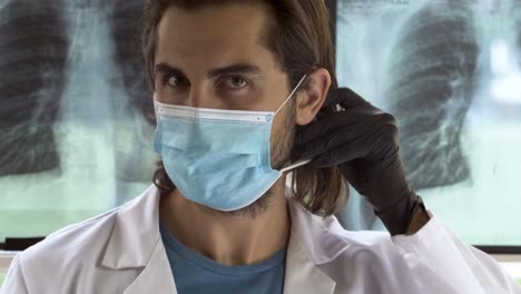 Doctor-staring-sharply-while-putting-on-mask---protective-goggles