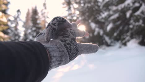Hand-with-gloves-grapping-for-the-sun-in-the-snowy-landscape-Location:-South-Tyrol
