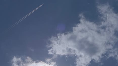 Handheld-tilt-up-of-beautiful-blue-sunny-day-afternoon-with-few-clouds-and-airplane-contrails