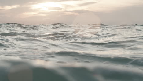 Tiefwinkelaufnahme-Einer-Großen-Welligen-Meeresoberfläche-Mit-Einem-Sonnenuntergang-Im-Hintergrund-In-Zeitlupe