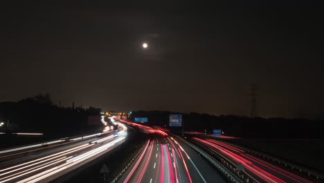 Timelapse-view-of-a-highway-near-Barcelona,-full-moon,-during-night-time,-in-Spain