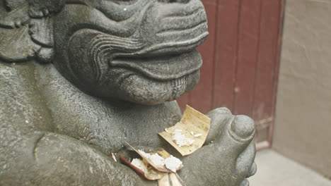 Detaillierte-Nahaufnahme-Der-Hinduistischen-Statue,-Die-Mit-Opfergaben-Geschmückt-Ist-Und-Das-Gesicht-In-Ubud-Auf-Bali,-Indonesien,-Aufdeckt