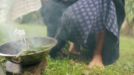 Woman-Burning---Fanning-Incense-Outdoors-on-Old-Fashioned-Rock-Stove