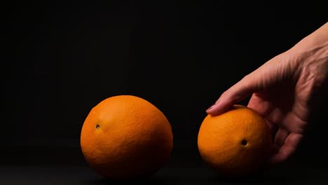 Woman-hand-pick-up-orange-fruit,-black-background