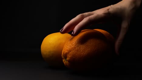 Statischer-Schuss-Der-Hand-Der-Frau-Orange-Frucht-Aufheben,-Schwarzer-Hintergrund