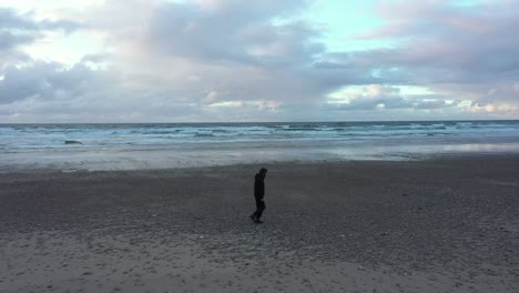 Man-walks-alone-along-empty-deserted-beach-during-pandemic-Covid-19