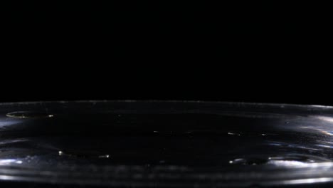 Droplets-of-Oil-Splash-in-Slow-Motion-into-Water-Isolated-on-Black-Background