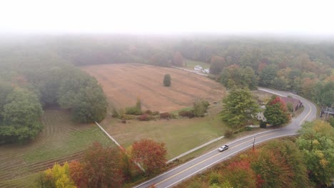 Aerial-footage-with-low-clouds,-fog,-fall-foliage,-and-farmlands