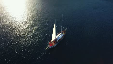 Aerial-shot-of-sailing-boat-in-blue-sea-at-sunset
